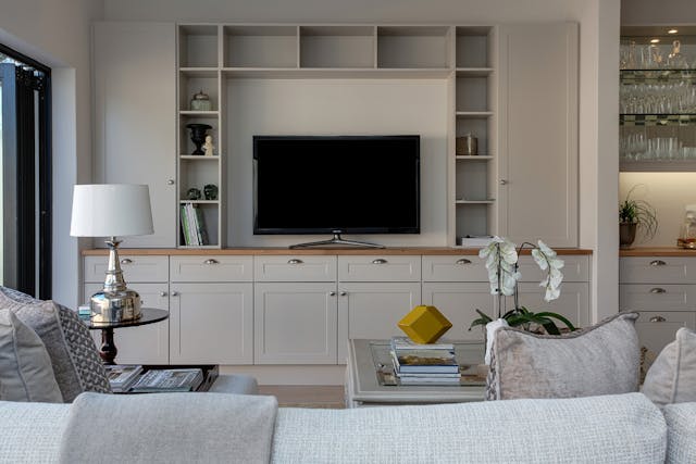 a white living room with a built-in bookshelf and entertainment system